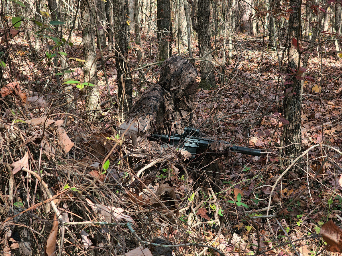 Hunter wearing Realtree Timber leafy suit seated in woodland
