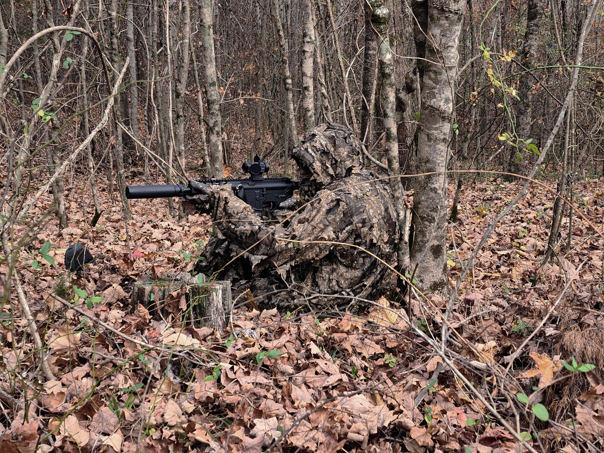 Hunter seated among trees wearing a Titan 3D Realtree Timber leafy suit